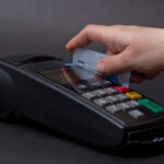 Hand Swiping Credit Card In Store. Female hands with credit card and bank terminal. Color image of a POS and credit cards